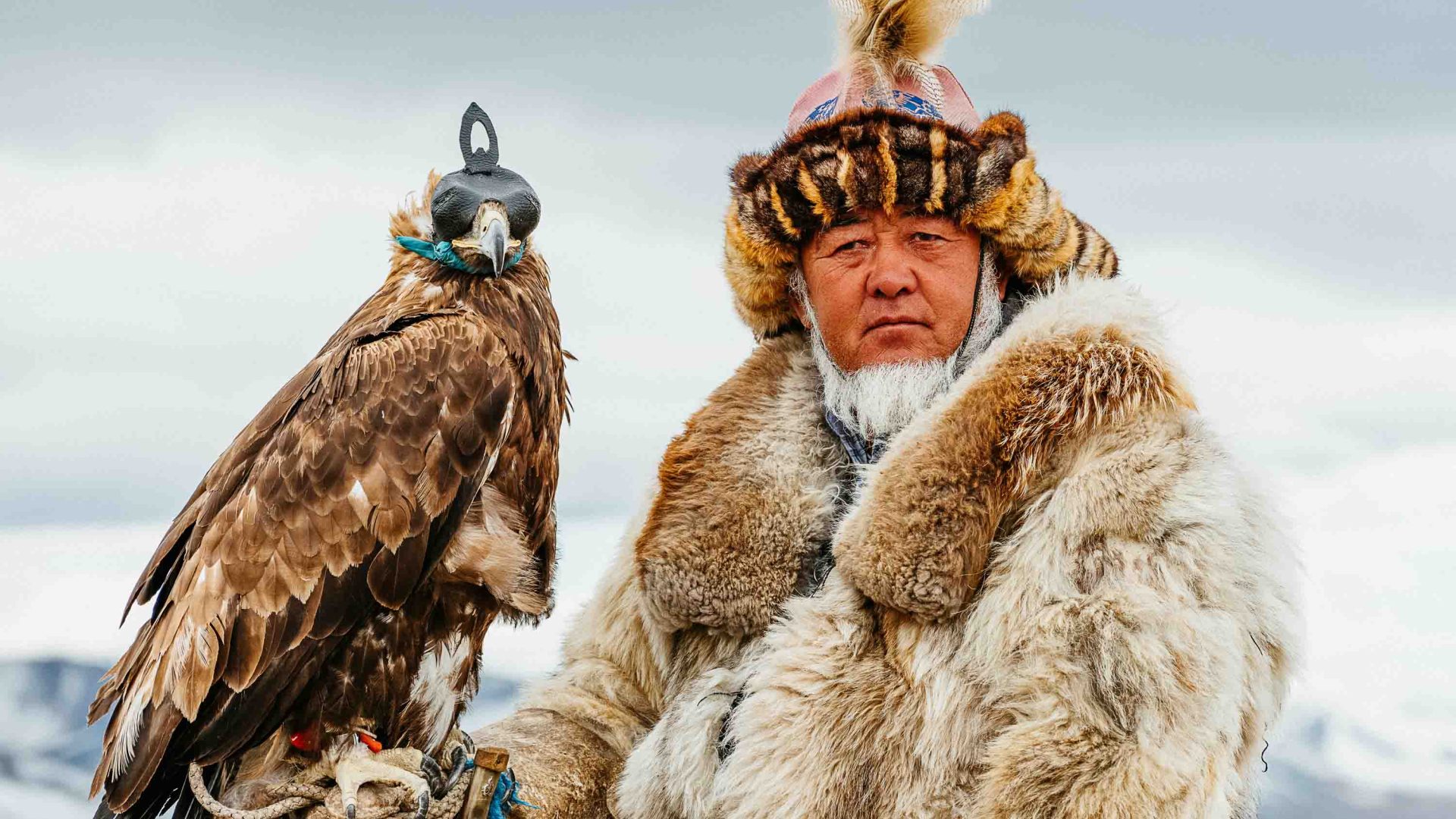 A man in Mongolia poses with one of his hunting birds.