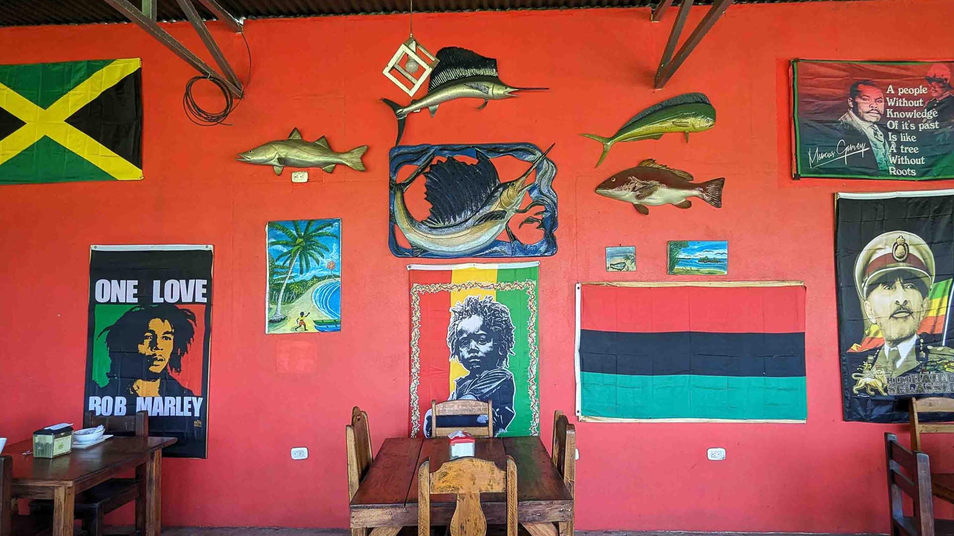 The Marcus Garvey quote and wall art on an orange wall with a Jamaican flag and fish images.