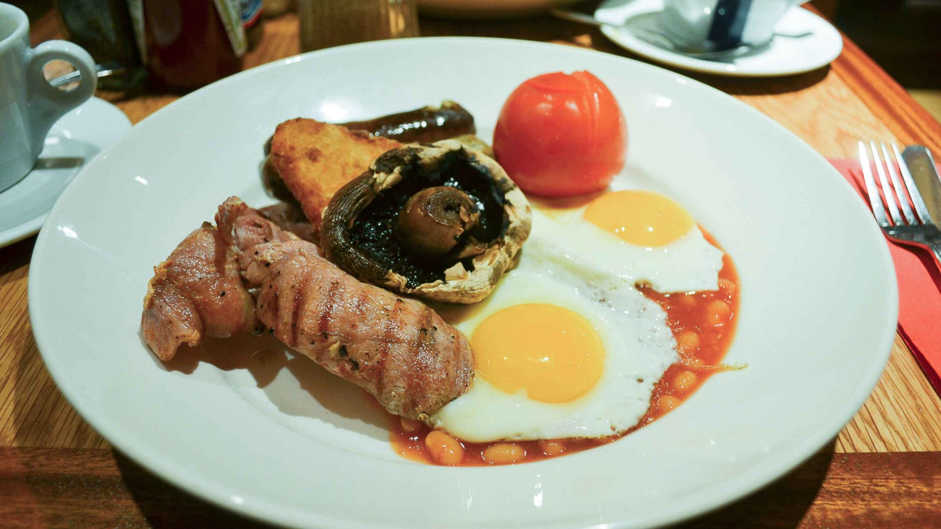 A fried breakfast of egg, bacon, mushroom, and tomato.