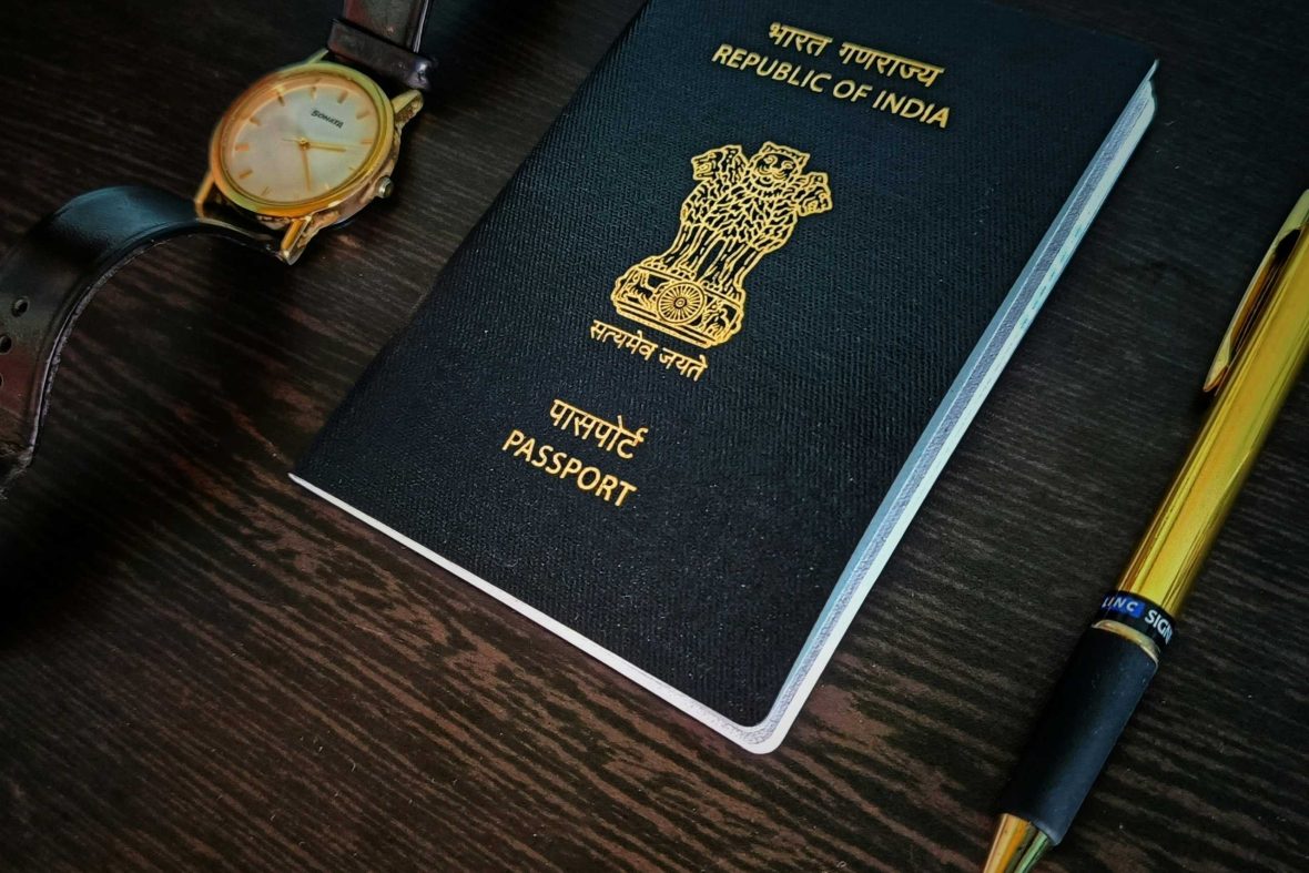 A watch, passport and pen laid out on a desk