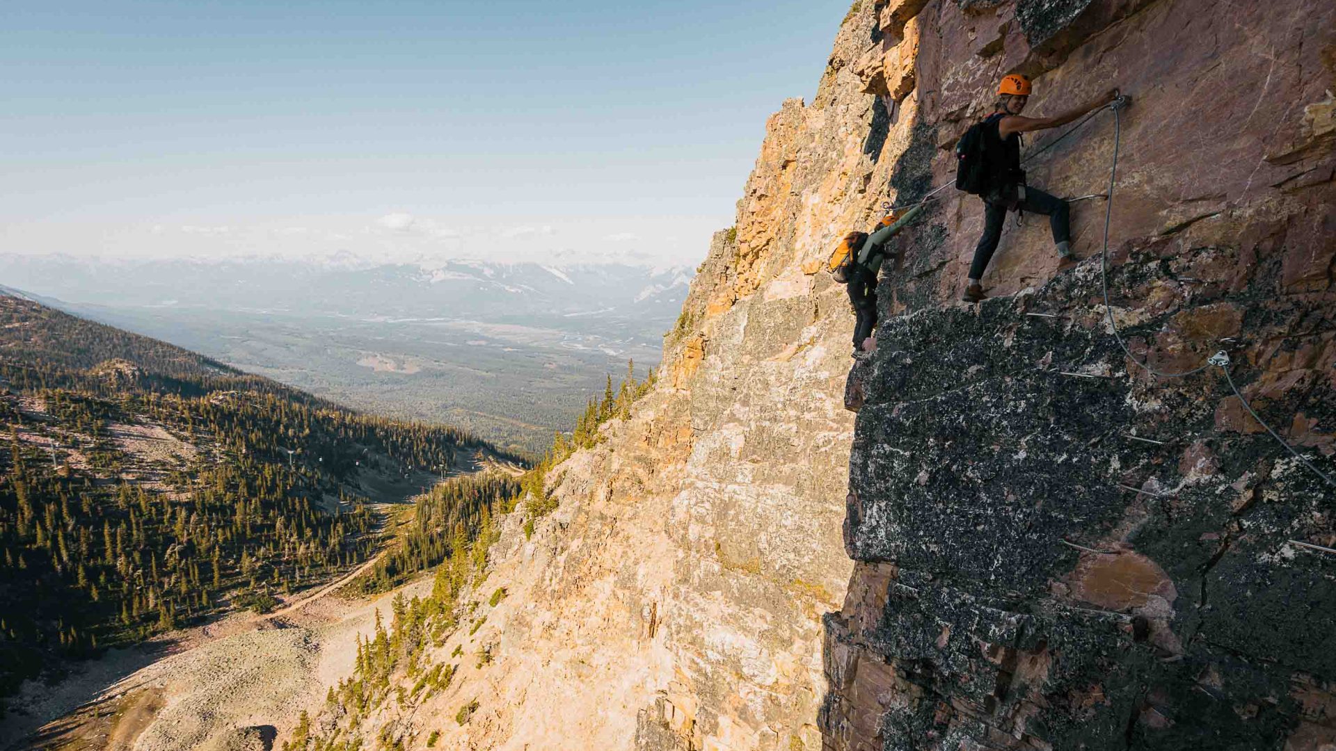 Two climbers on a via ferrata on a rock face.