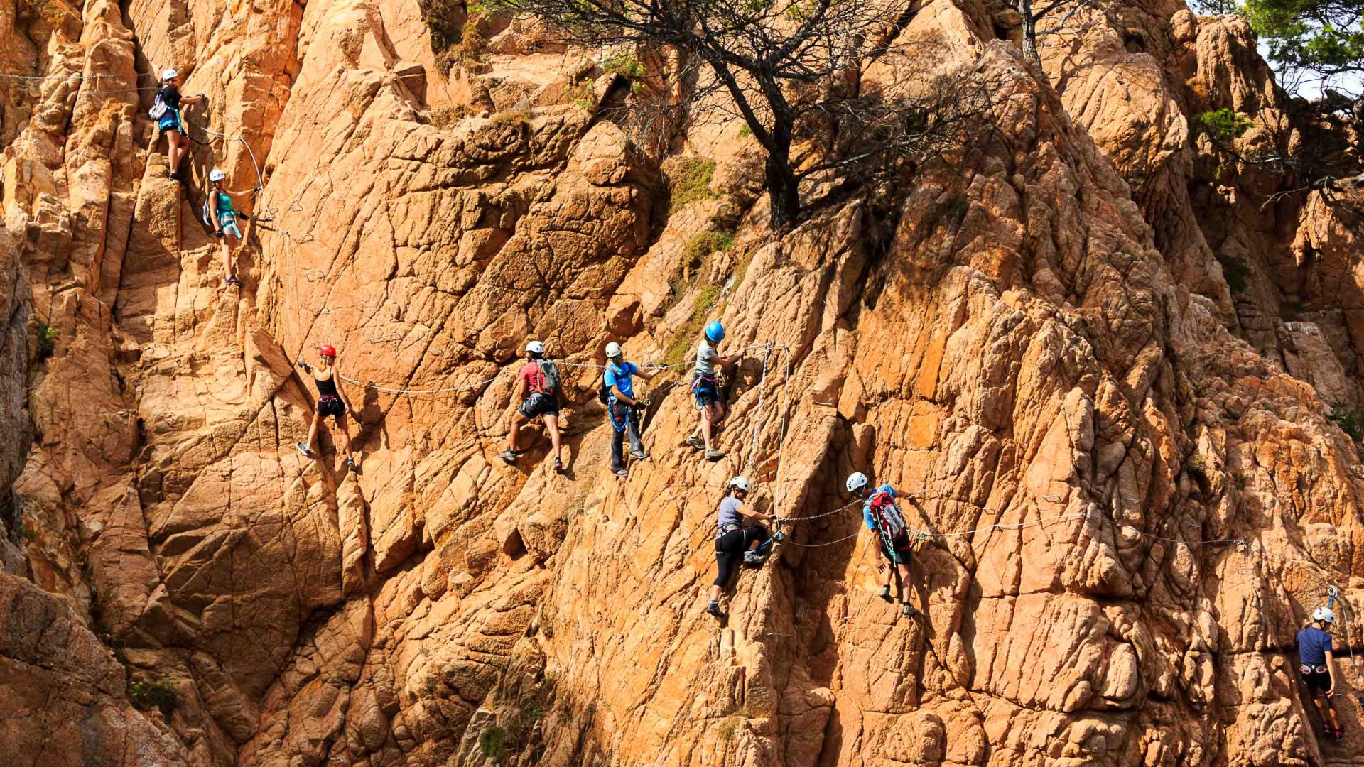 A line of people traverse a rock face.