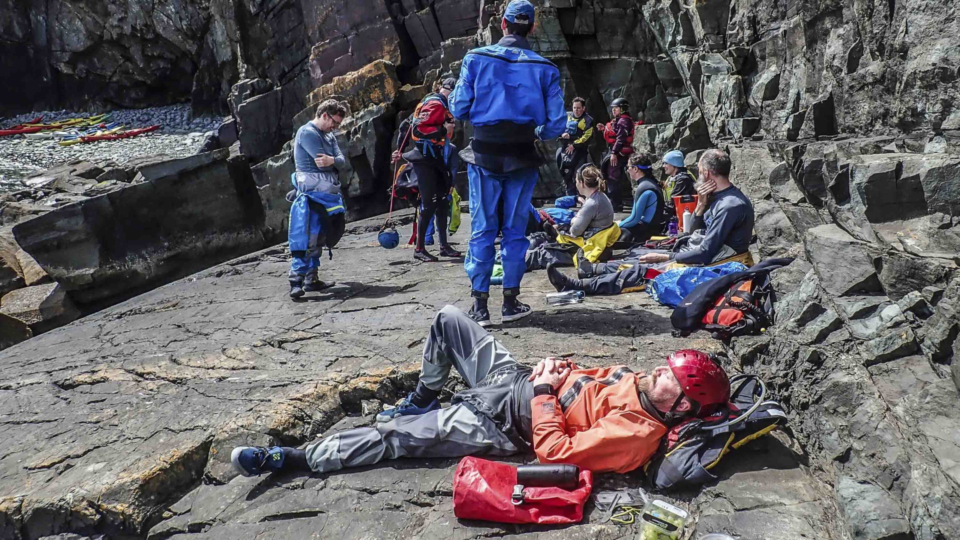 A group of kayakers rest on a beach.