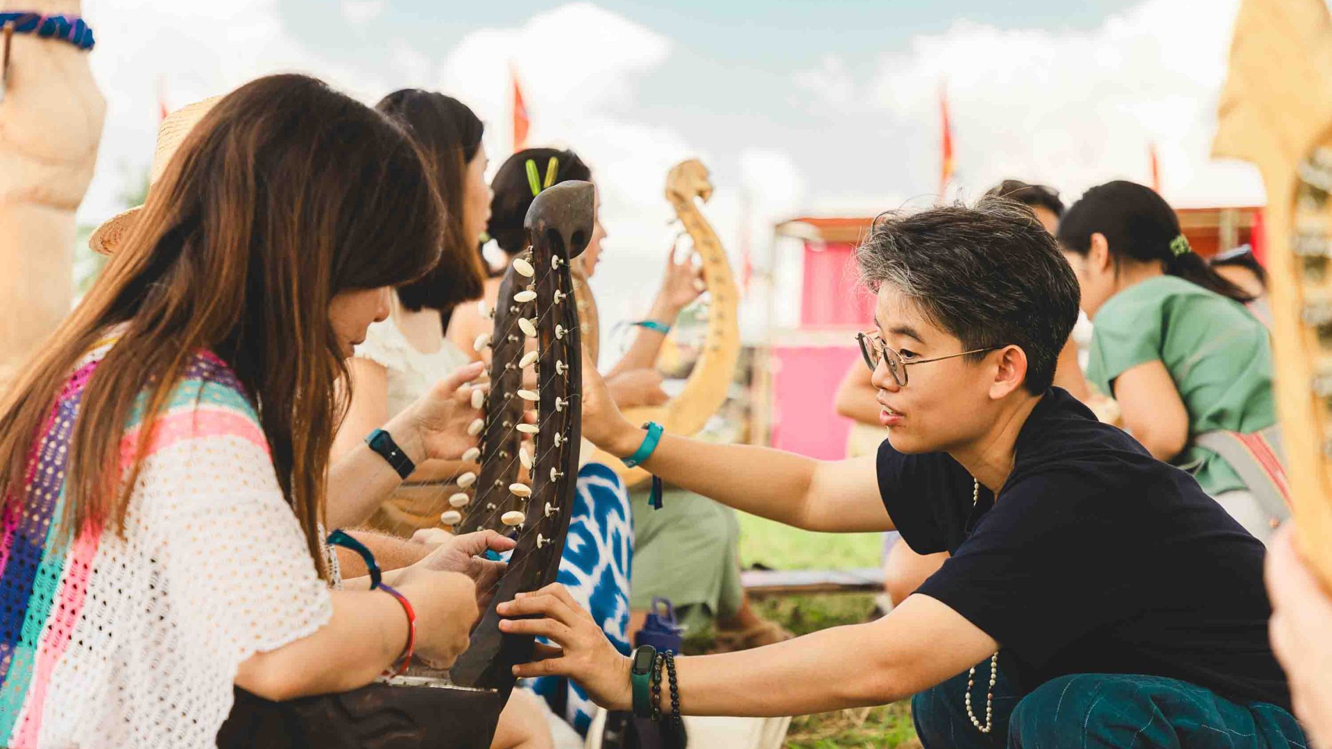 Mae teaches a participant about an instrument at a Tae Na Gu workshop.