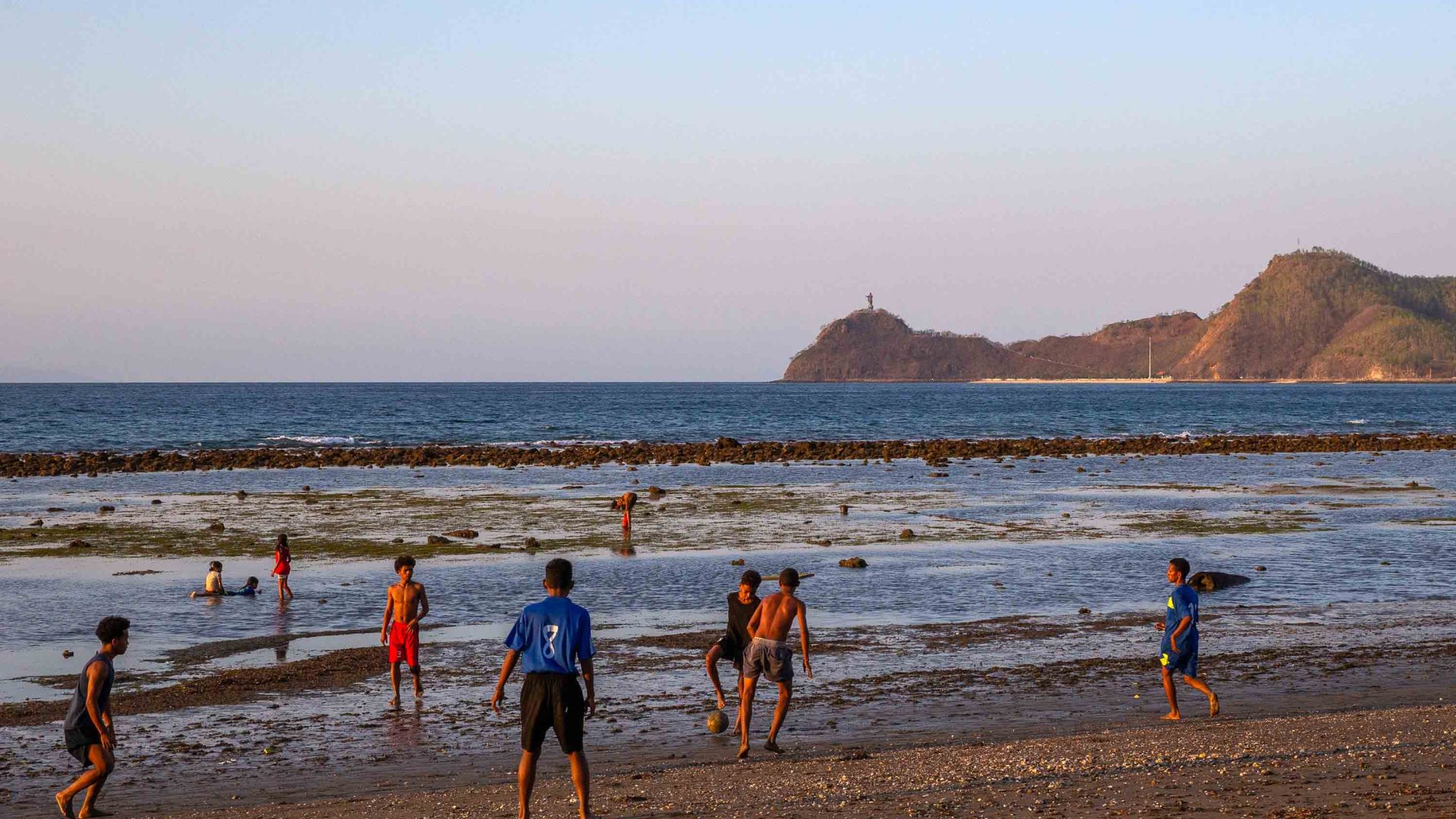 Young children play soccer on the beach in Timor Leste.